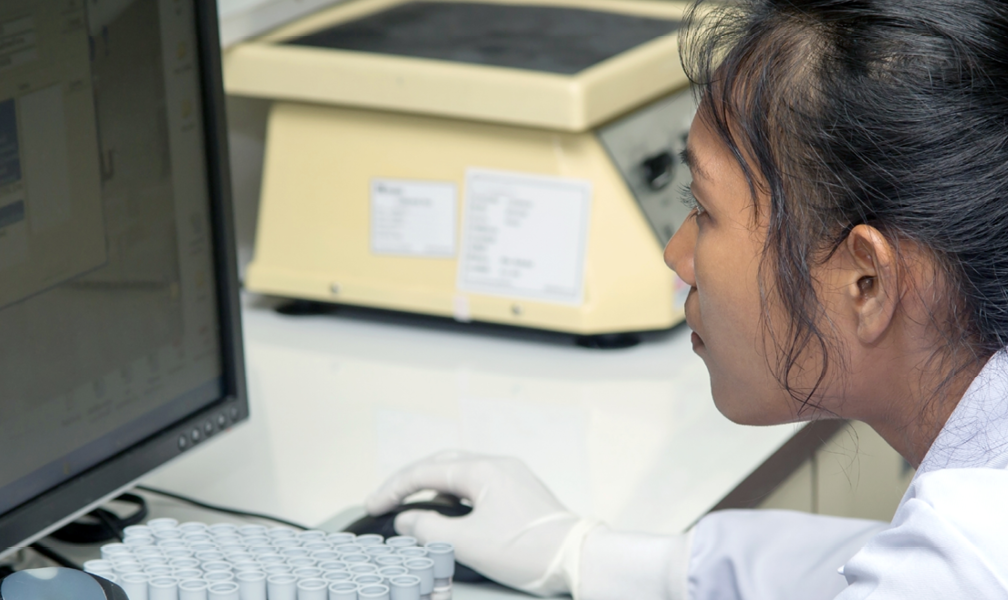 Female pharmacist in lab coat looking at screen