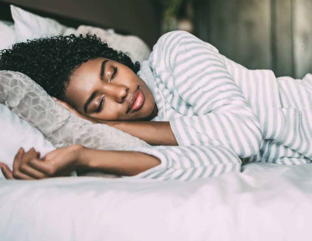 close up of a pretty black woman with curly hair sleeping in bed closed eyes